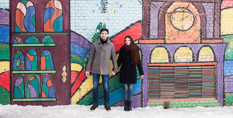 Plakat couple in love on the background of a painted wall in winter in a coat
