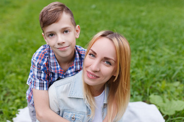Portrait of happy young mother with her son having fun together. kissing and Embrace outdoors