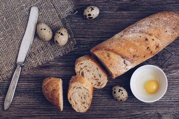 Bread and quail eggs on a wooden table, top view.