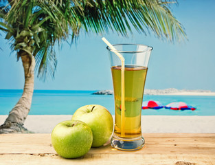 Glass of apple juice on a beach table