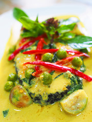 Thai local traditional homemade fusion food: Grilled fried sliced cut salmon, thick spicy green curry, coconut milk, "Kang Kiew Whan", pea, eggplant, decorated red chili, basil leaf, vertical close up