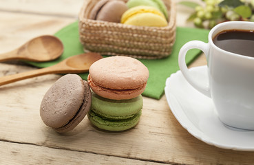 French cookies on a wooden table and coffee in a white mug, macaroons