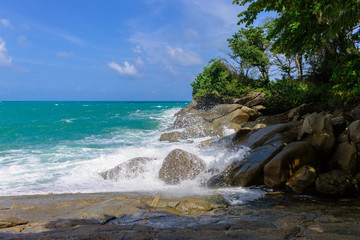Fototapeta na wymiar Waves hit rocks on the shore of the blue sea