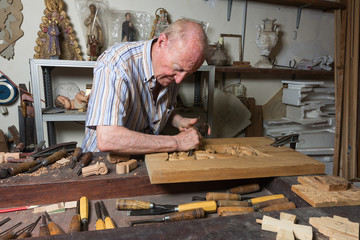 Maestro tallista trabajando la madera con martillo y gubia.