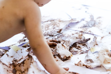 baby painting with hands with chocolate