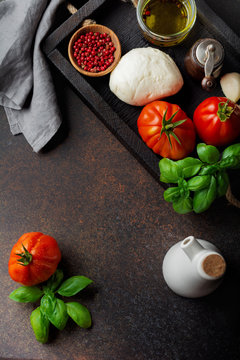 Ingredients for making traditional italian salad caprese in  wooden box on dark slate or rusty metal background.  Selective focus. Top view. Copy space.