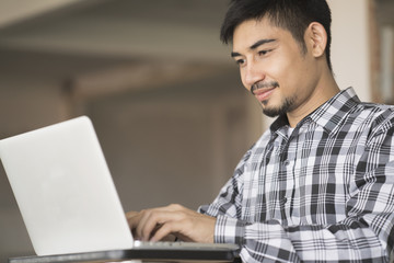 young asian man using laptop at home