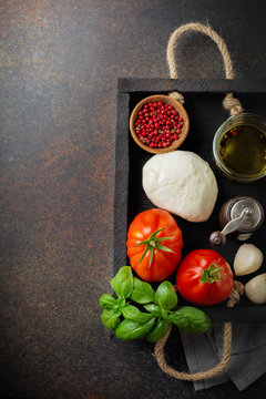 Ingredients for making traditional italian salad caprese in  wooden box on dark slate or rusty metal background.  Selective focus. Top view. Copy space.