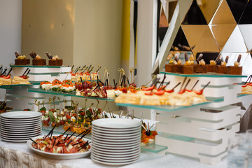 Beautifully decorated catering banquet table with burgers profiteroles salads and cold snacks