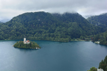 Bled with lake, island, castle and mountains in background in misty and rainy day