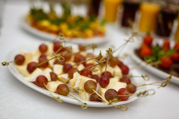 Refined appetizer of cheese fruits and berries pieces of cheese with pricked skewers berries