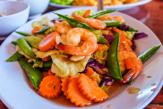 Mixed vegetables and shrimps with oyster sauce serve on dish.