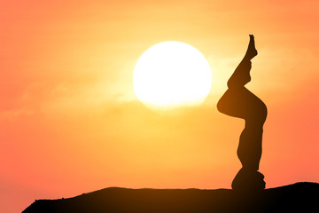 Silhouette of a beautiful Yoga woman with sun background 