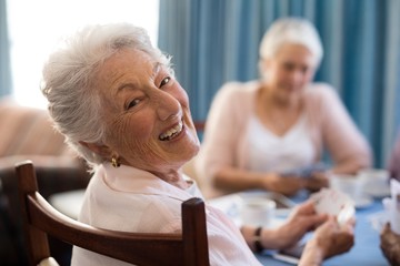 Smiling senior woman playing cards with friends - Powered by Adobe