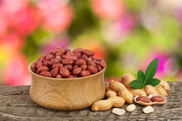peanuts with leaf in bowl on old wooden table with a blurry garden background
