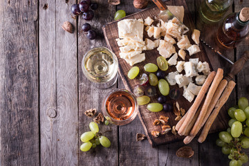 Different kinds of cheeses, wine, fruits and snacks on rustic wooden table . still life concept