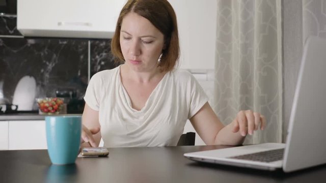 Woman working on laptop by the table at home
