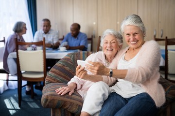 Portrait of smiling senior woman taking selfie with friend