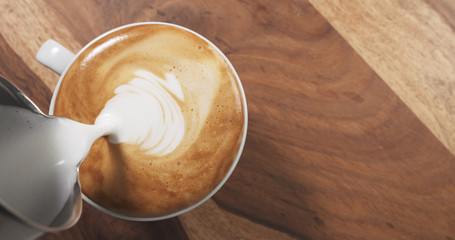 top view pour steamed milk into cappuccino on wood table