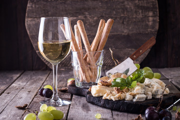 Different kinds of cheeses, wine, fruits and snacks on rustic wooden table . still life concept