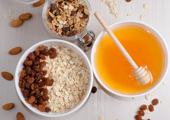 Healthy Breakfast. Oatmeal with raisins in white bowl. Almonds, honey on white  table background