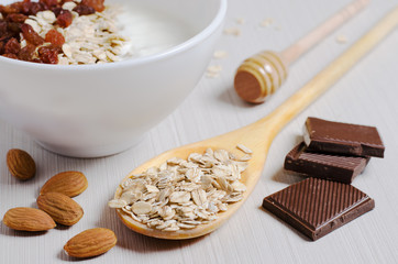 Oatmeal with raisins and yogurt. Oatmeal in the wooden spoon. Almond, chocolate