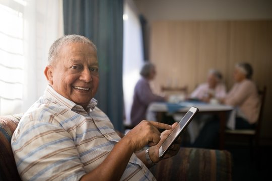 Portrait of smiling senior man using digital tablet