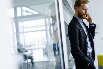 Businessman with ginger hair using mobile phone in office