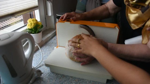 Germany old women use bread slicer or bread cutter cutting bread at kitchen in home in Heidelberg, Germany