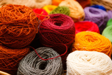 Fototapeta na wymiar Balls of yarn scattered near the basket lots of colorful threads on old background yarns