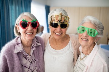 Portrait of smiling senior women wearing novelty glasses - Powered by Adobe