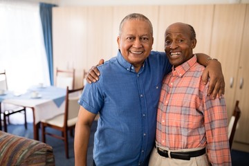 Fototapeta premium Portrait of smiling senior friends standing with arms around