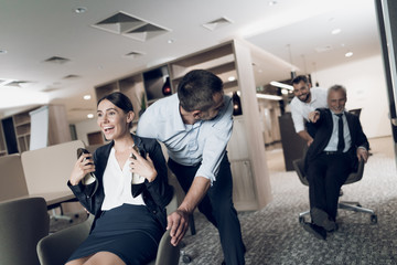 Office workers have fun in the office. They arranged races on office chairs