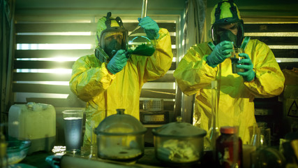 In the Underground Drug Laboratory Two Clandestine Chemists Wearing Protective Masks and Coveralls Test Cooked Drug's Purity and Strength.