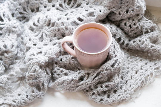 Warm and comfy autumn or winter concept. Book, cup of lemon tea and sweater on wooden window sill in old house. Reading and relaxing in cold fall weather at home. Quiet silent homely scene.