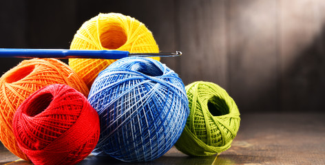 Colorful yarn for crocheting and hook on wooden table