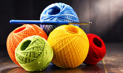 Colorful yarn for crocheting and hook on wooden table