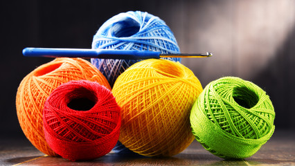 Colorful yarn for crocheting and hook on wooden table