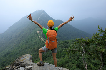 successful woman hiker open arms to the great wall on the top of mountain