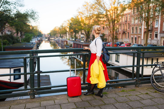 The traveler with suitcase is walking in the street of Amsterdam city in autumn