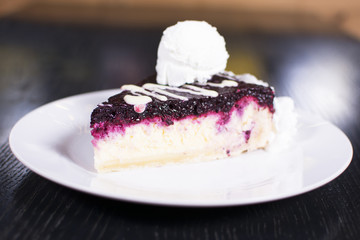 Blueberry cheesecake on a ceramic white plate with ice cream. Delicious dessert in a restaurant.