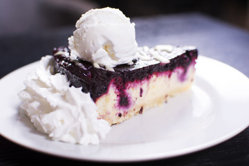 Blueberry cheesecake on a ceramic white plate with ice cream. Delicious dessert in a restaurant.