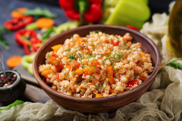 Vegetarian crumbly pearl barley porridge with vegetables  in a dark background