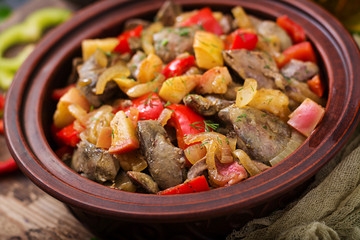 Roast chicken liver with vegetables on wooden background.