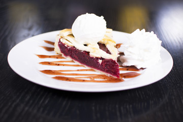 Delicious homemade cherry pie with a flaky crust top view. Ice cream balls on a plate.