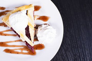 Delicious homemade cherry pie with a flaky crust top view. Ice cream balls on a plate.