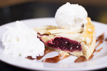 Delicious homemade cherry pie with a flaky crust top view. Ice cream balls on a plate.