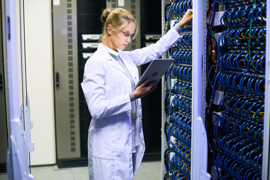 Side view portrait of young woman wearing lab coat  working with supercomputer in research center, copy space