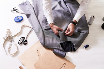 Top view of tailors table with  unrecognizable man making jacket for bespoke  suit