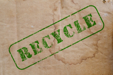 green recycle stamp on a piece of old brown stained cardboard